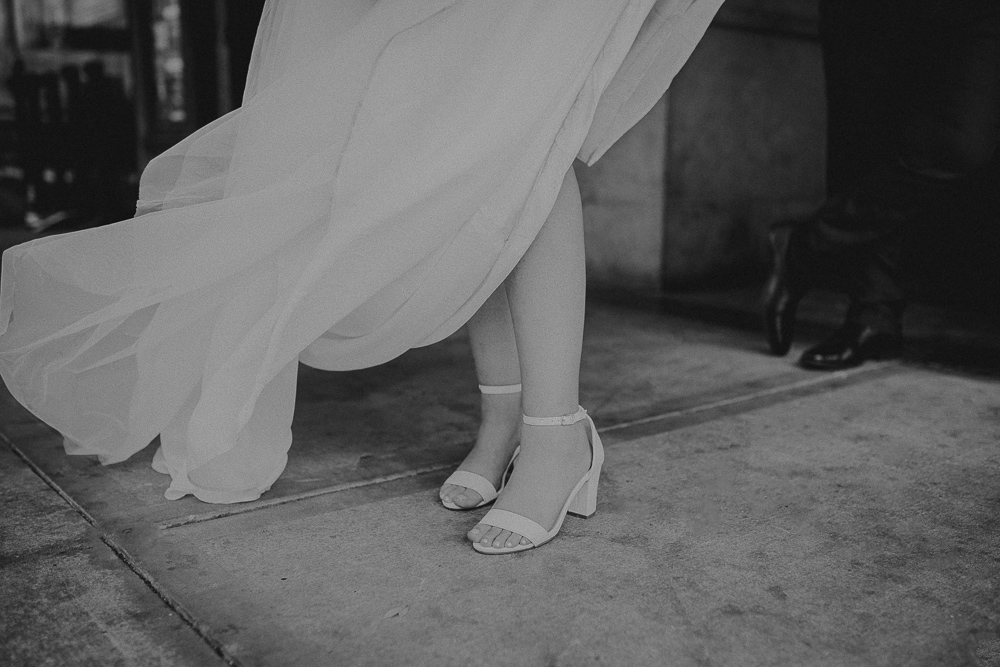 a close up of the brides shoes as she stands on the side walk after their tampa courthouse wedding
