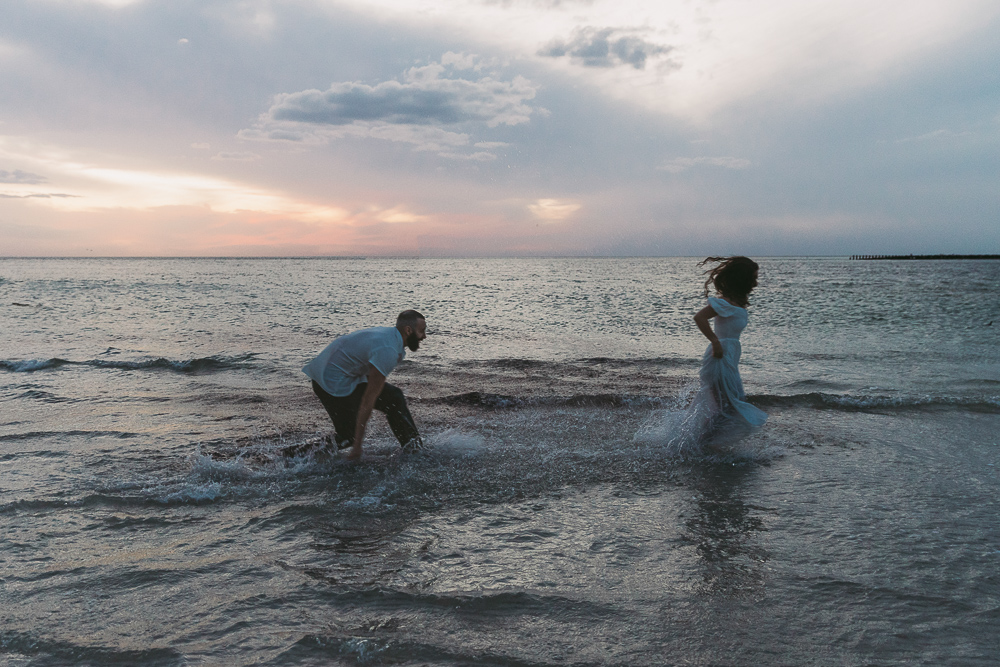 couple splashing in the ocean during engagement session in sarasota 