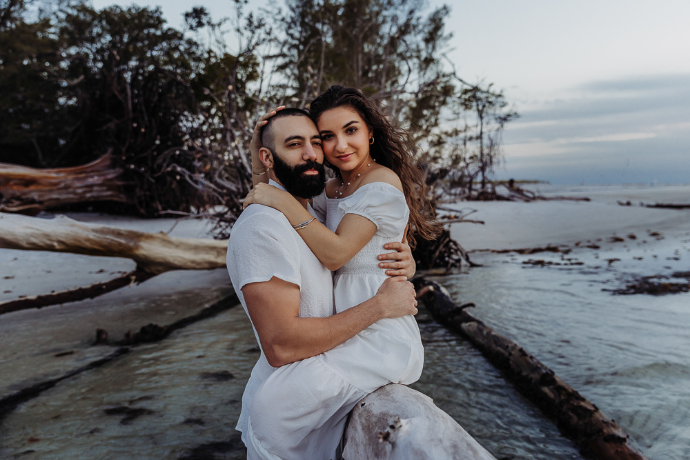 portrait of couple on fallen tree on the beach in anna maria island outside of sarasota 