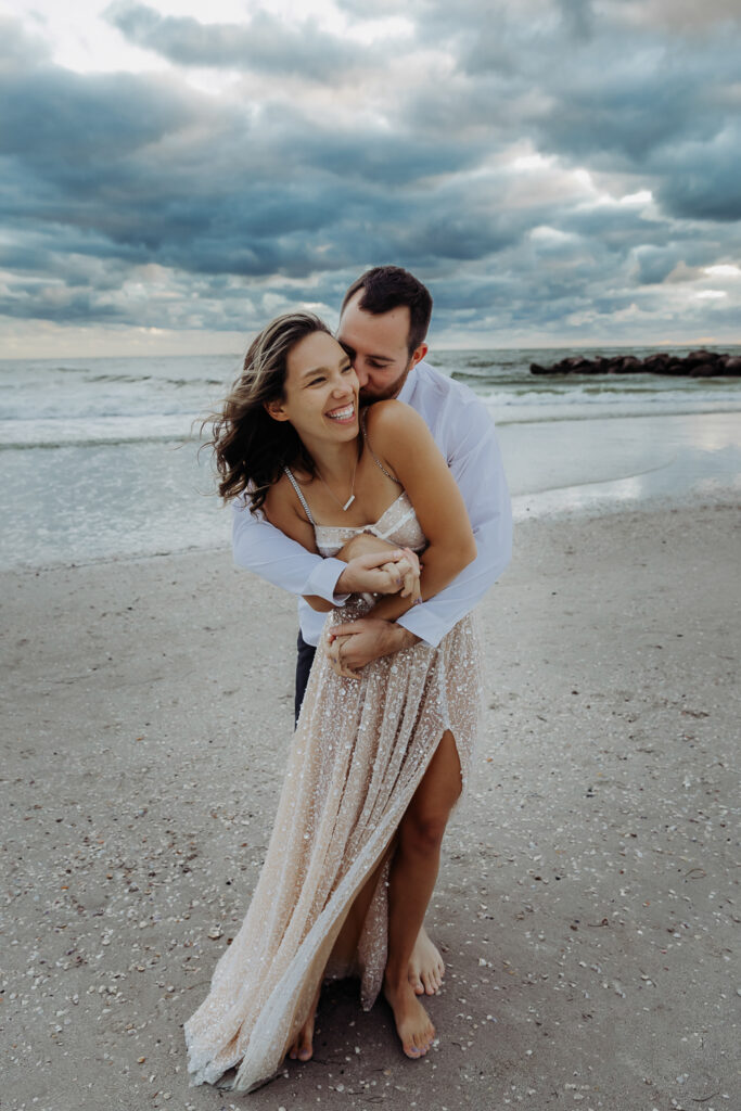 engaged couple hugging on the beach during their engagement session with a tampa wedding photographer