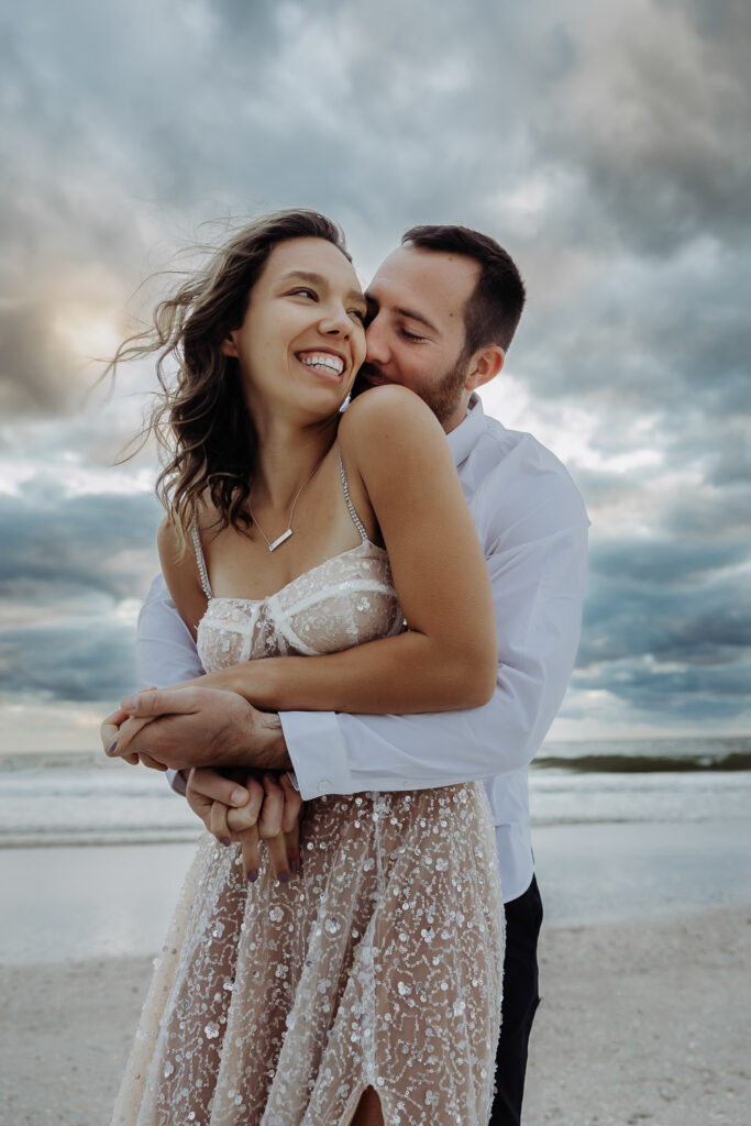 engaged couple hugging on the beach during their engagement session with a tampa wedding photographer