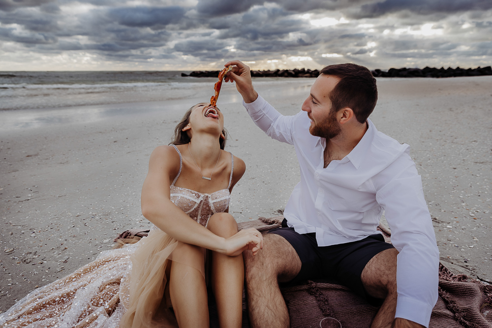 newly engaged couple eating pizza on st pete beach during their engagement session with a tampa wedding photographer