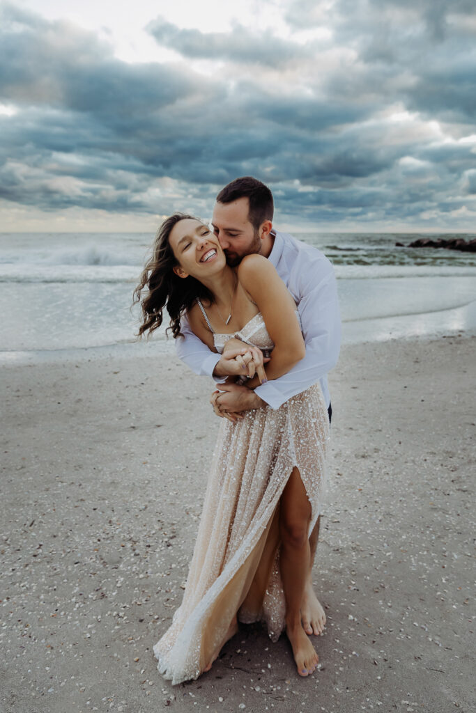 engaged couple hugging on the beach during their engagement session with a tampa wedding photographer