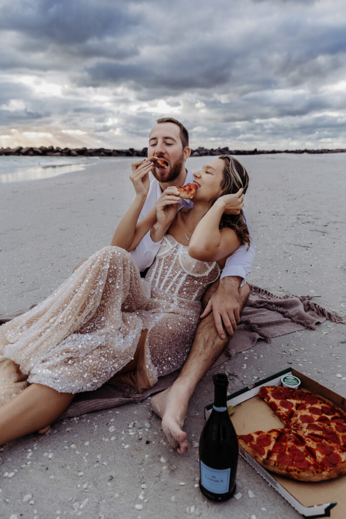 newly engaged couple eating pizza on st pete beach during their engagement session with a tampa wedding photographer