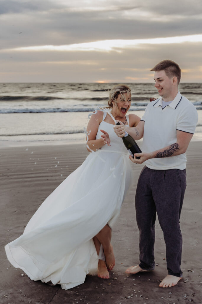 couple popping champagne that they remembered to bring from their elopement checklist 