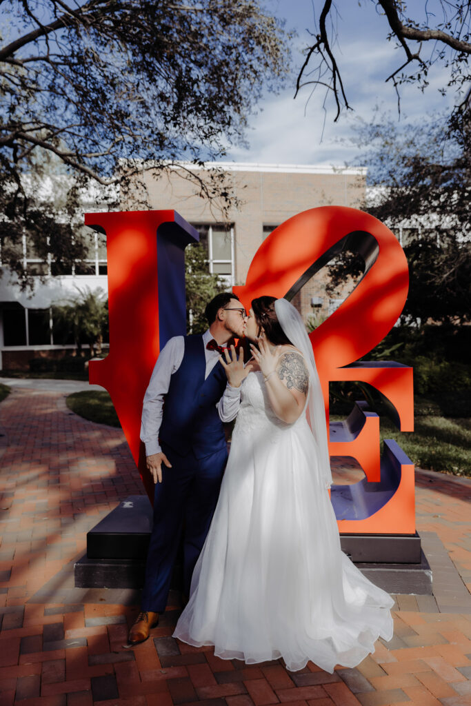 couple kissing in front of a LOVE sign in downtown tampa