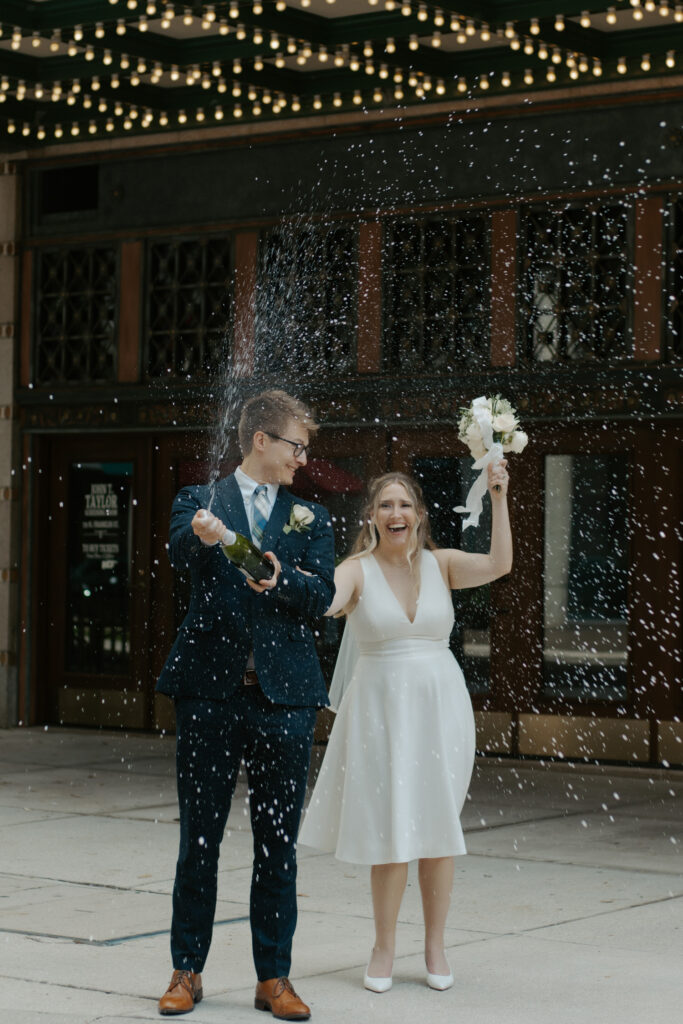 couple popping champagne after their elopement in front of the tampa theater 