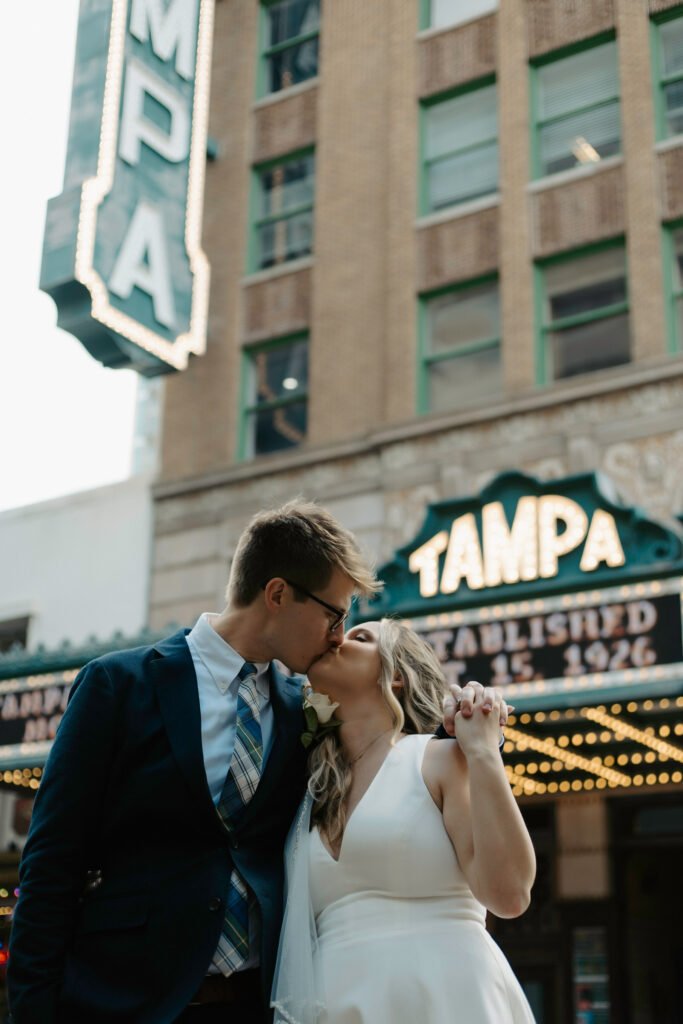 couple sharing a kiss in front of the tampa theater after their elopement 