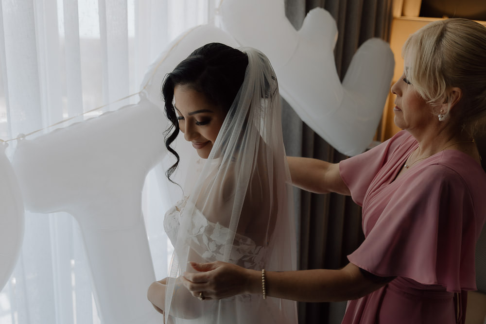 bride getting ready with her mom before her ceremony