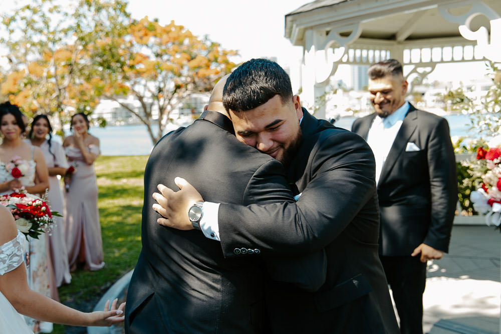 groom and brides dad share a hug during the wedding ceremony 